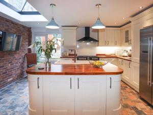 a kitchen with white cabinets and a wooden counter top at Swn Y Mor in Criccieth