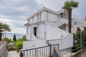 une maison blanche avec des palmiers devant elle dans l'établissement Apartment Vita, à Rijeka
