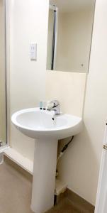een witte wastafel in een badkamer met een spiegel bij The Queens Head in Stratford-upon-Avon