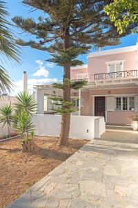a pink house with a tree in front of it at Villa Arokaria in Stení
