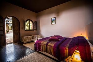 a bedroom with a bed and a living room with a couch at Ryad de Vignes " Le Val d'Argan " in Ounara