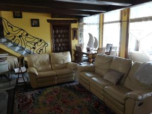 una sala de estar con 2 sofás y un piano en Villa Rural "La casa de ANA", en Muelas de los Caballeros