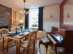 a dining room with a table and a piano at 12 Victoria Terrace in Nantlle