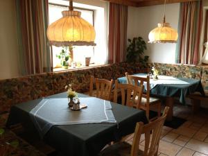 a dining room with two tables and chairs and windows at Berggasthof Hintergföll in Unken