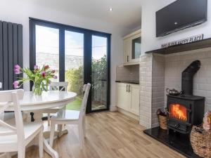 a kitchen and dining room with a fireplace and a table and chairs at Achipur in Porthmadog