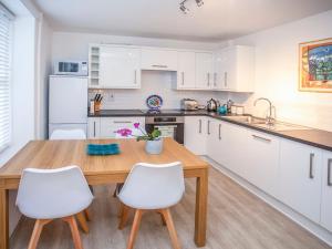 a kitchen with a wooden table and white chairs at Bryn Teg Cottage in Menai Bridge +14 photos