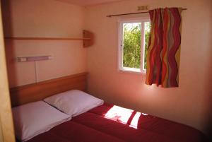a small bed in a room with a window at LES PIERRES CHAUDES in Veyrignac