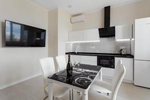 eine Küche mit einem schwarzen Tisch und weißen Stühlen in der Unterkunft Feeria Apartment in Odessa