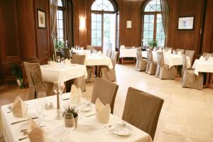 un comedor con mesas y sillas blancas en Hotel Villa Altenburg, en Pößneck