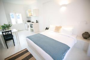 Habitación blanca con cama grande y escritorio. en Apanomeria Boutique Residence en Oia