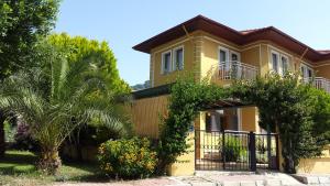 una casa amarilla con una valla y árboles en Sirman Apart Hotel, en Sarigerme