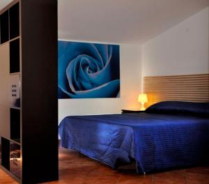 a bedroom with a blue bed with a painting on the wall at Villa Smeraldo Roma in Infernetto