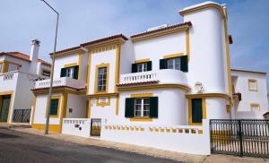 a white and yellow house with green shutters at Villa Do Mar SW in Zambujeira do Mar