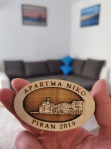 eine Hand, die eine Medaille mit einem Bild eines Ramnma nikko hält in der Unterkunft Apartment Niko in Piran