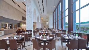 um restaurante com mesas, cadeiras e janelas em Radisson Hotel Agra em Agra