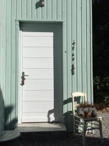 una puerta blanca de garaje en un edificio verde con una silla en Au Coin des Cerisiers en Montclus