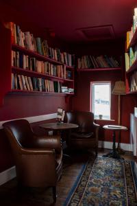 een bibliotheek met 2 stoelen, een tafel en boeken bij The Carden Arms in Tilston