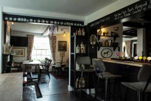 a bar in a restaurant with a table and chairs at The Carden Arms in Tilston