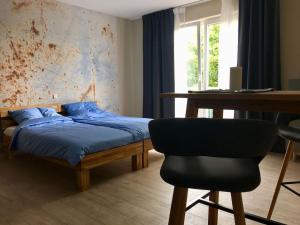 een slaapkamer met een bed, een bureau en een stoel bij 2nd Home Appartements 7 in Nieder-Olm