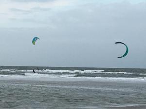 dos personas están volando cometas en la playa en Apartments Lille Hus, en Sankt Peter-Ording