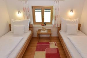 two beds in a small room with a table at Hof Lässer in Möggers