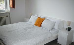 a white bed with an orange pillow on it at City Center Apartment II in Nitra
