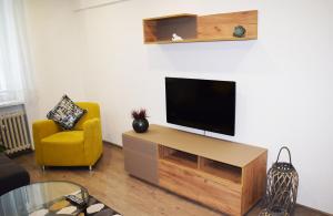 un soggiorno con TV e sedia gialla di Center City Apartment II a Nitra