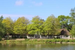 ein Haus am Wasser mit Bäumen in der Unterkunft Suite in Nieblum - Martina Christiansen in Nieblum