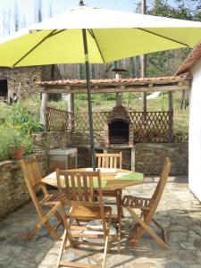 a table and chairs under a yellow umbrella at Casa da Eira in Cerdeira +4 photos