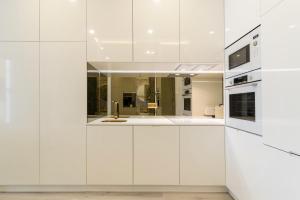 una cocina blanca con armarios blancos y fregadero en Ocean View Luxury Suite & Terrace Estoril, Cascias, en Estoril