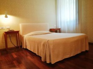 a bedroom with a bed and two tables and a window at LOCANDA PERINELLA in Castelgomberto