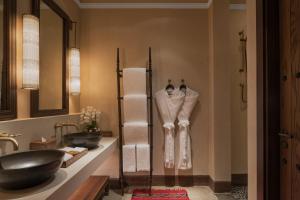 a man standing in a bathroom next to a sink at The Chedi Al Bait, Sharjah in Sharjah