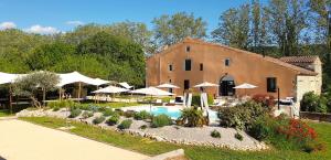 a building with a swimming pool in front of a house at Domaine De Pradaous in Reillanne