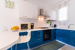 a blue and white kitchen with blue cabinets at Apartment window on the sea in Santo Stefano di Camastra