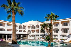un hotel con palmeras y una piscina en Hotel Vibra Bossa Flow - Adults only, en Playa d'en Bossa