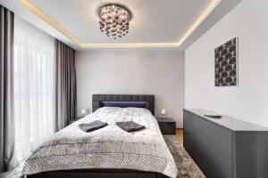 - une chambre avec un lit et un lustre dans l'établissement Toress Apartamenty Deptak, à Szczecin