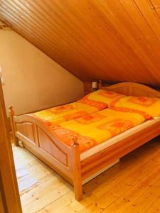 a bed in a room with a wooden ceiling at Rozmaring Ház in Balatonlelle
