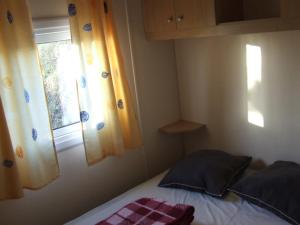 Habitación pequeña con cama y ventana en camping Manex, en Saint-Pée-sur-Nivelle