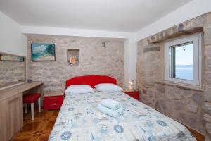 a bedroom with a bed and a stone wall at VILLA FENIX PODGORA in Podgora