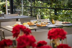 una mesa con platos de comida y flores rojas en Hotel Livia, en Gargnano