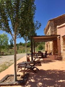 un grupo de mesas de picnic y un árbol al lado de un edificio en Mas de León en Cortes de Arenoso