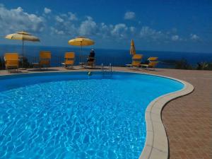a swimming pool with chairs and umbrellas and the ocean at Hotel La Cometa in Diamante