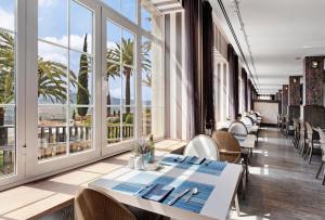 - un restaurant avec des tables, des chaises et de grandes fenêtres dans l'établissement Catalonia Reina Victoria, à Ronda