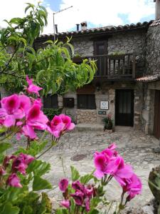 une maison avec des fleurs roses devant elle dans l'établissement El Balcon de Los Sueños, à Trevejo