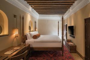 a bedroom with a bed and a desk and a television at The Chedi Al Bait, Sharjah in Sharjah +103 photos