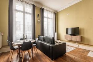 a living room with a couch and a table and a tv at Le cœur de Reims, la mairie et le Boulingrin in Reims