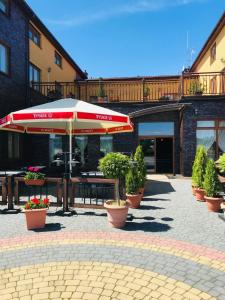 une terrasse avec un parasol, des tables et des plantes en pot dans l'établissement Zajazd Hubus, à Grabowo-Olszewo