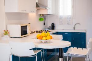 a white kitchen with a bowl of fruit on a table at Apartment window on the sea in Santo Stefano di Camastra