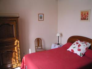 a bedroom with a red bed and a dresser at La Ferme Du Luc in Le Chêne