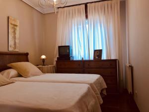 une chambre avec deux lits et une fenêtre avec une télévision dans l'établissement Llanes mar y montaña, à Llanes
